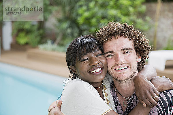 Porträt glückliches junges multiethnisches Paar  das sich am Pool umarmt