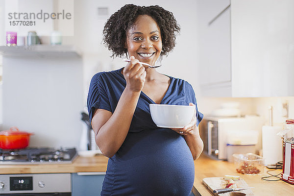 Porträt glückliche schwangere Frau beim Essen in der Küche