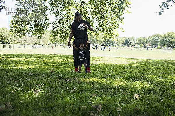 Vater und Kleinkind Sohn spielen mit Fußball im Park