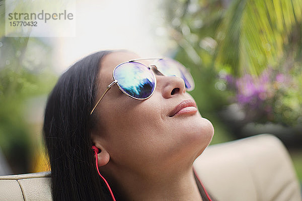 Close up heitere Frau mit Sonnenbrille beim Sonnenbaden  Musik hören mit Kopfhörern