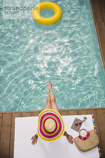 Frau mit Sonnenhut entspannt  Sonnenbaden am Sommerpool