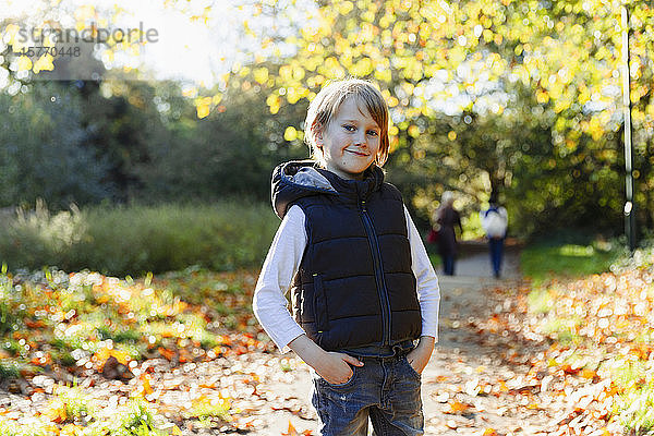 Portrait selbstbewusster Junge im sonnigen Herbstpark