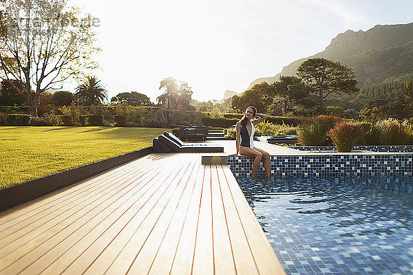 Junge Frau im Badeanzug entspannt sich am sonnigen  luxuriösen Swimmingpool  Kapstadt  Südafrika