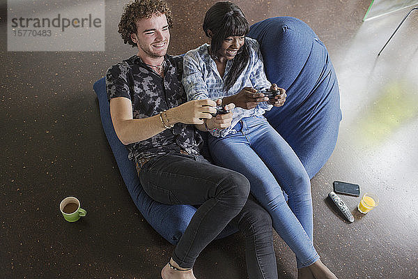 Glückliches junges Paar spielt Videospiel auf Sitzsack