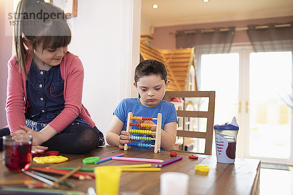 Konzentriertes Kind mit Down-Syndrom spielt mit Spielzeug am Tisch