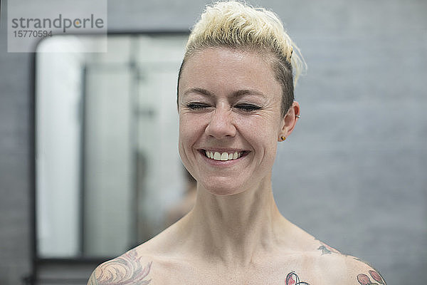 Porträt glückliche sorglose Frau mit Tattoos lachend im Badezimmer