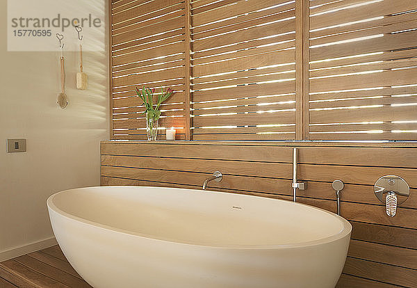 Badewanne und hölzerne Fensterläden in einem modernen  luxuriösen Haus zeigen das Innere des Badezimmers