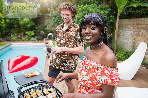 Portrait glückliches junges multiethnisches Paar beim Grillen am Pool