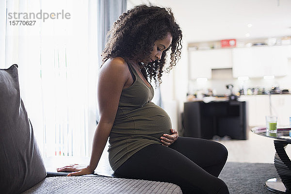 Gelassene junge schwangere Frau berührt den Bauch