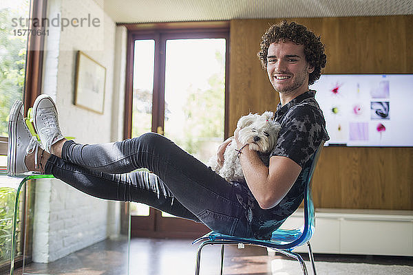 Porträt glücklicher junger Mann mit Hund im Heimbüro