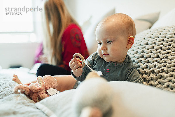 Niedliche neugierige Baby Mädchen spielen mit Spielzeug auf dem Bett