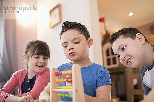 Junge mit Down-Syndrom und Geschwister spielen mit Spielzeug