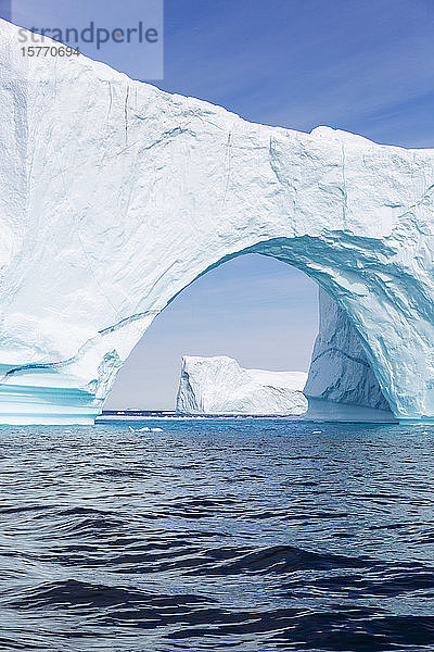 Majestätischer Eisbergbogen über dem sonnigen blauen Atlantischen Ozean Grönlands