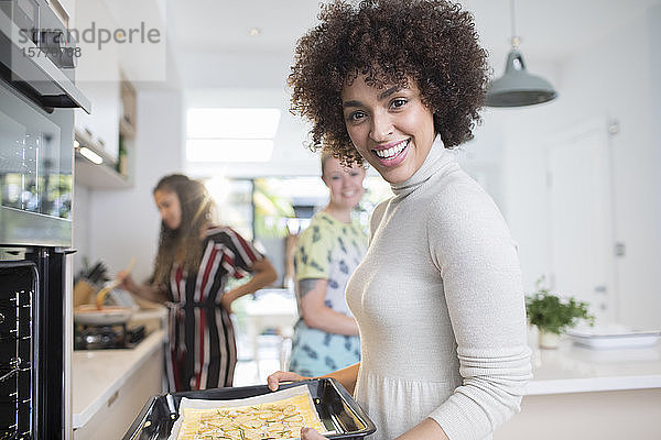 Portrait glückliche junge Frau beim Kochen mit Freunden in der Küche