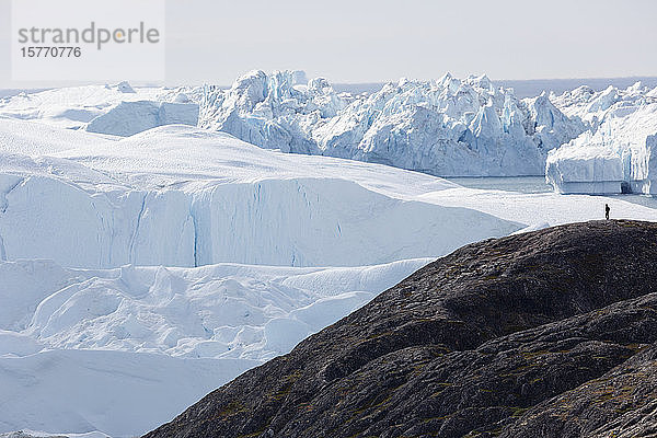 Mann auf Klippe mit Blick auf die majestätischen polaren Gletscher Grönlands