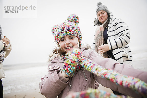 Porträt glückliches sorgloses Mädchen in warmer Kleidung am Winterstrand