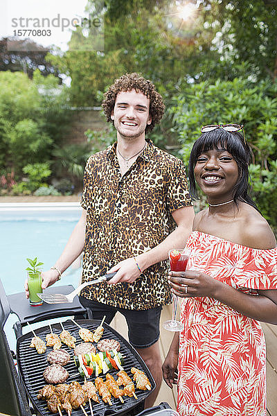 Portrait glückliches junges multiethnisches Paar beim Grillen am Pool