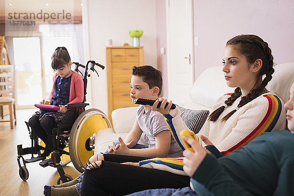 Familie mit Down-Syndrom-Kind beim Fernsehen im Wohnzimmer