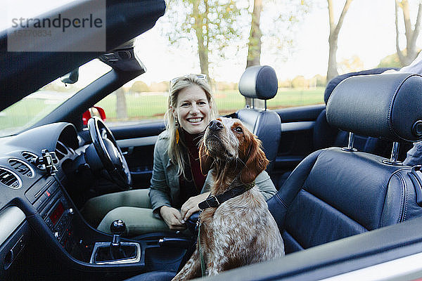Portrait glückliche Frau im Cabrio mit Hund