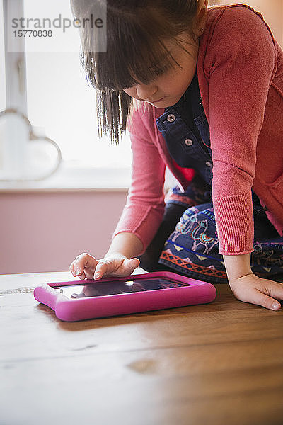 Mädchen benutzt digitales Tablet am Tisch