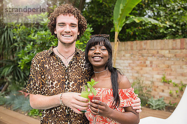 Portrait glückliches multiethnisches Paar trinkt Cocktails auf der Terrasse