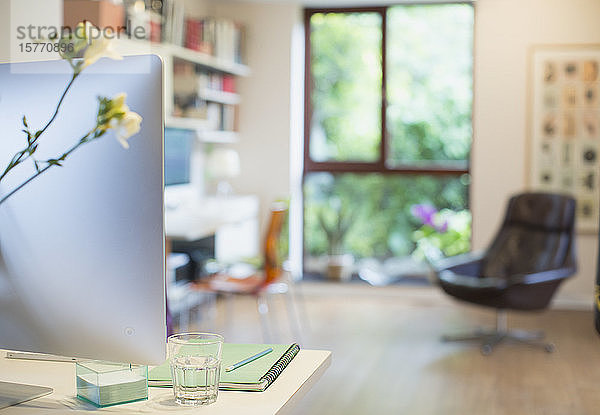 Computer und Blumen auf dem Schreibtisch im Heimbüro