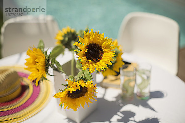 Sonnenblumen auf dem sonnigen Terrassentisch am Pool