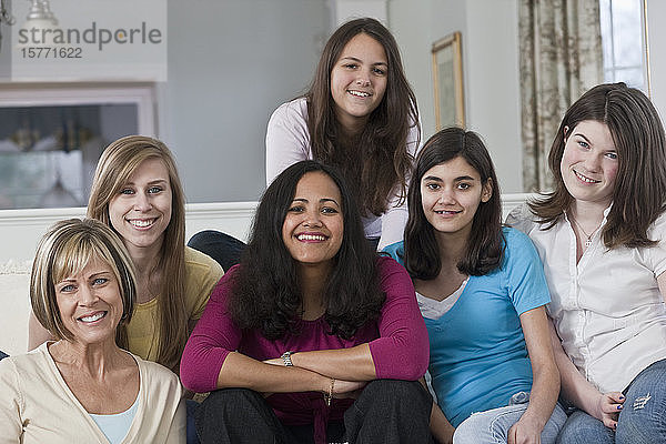 Porträt von zwei Müttern und vier Mädchen im Teenageralter  die zu Hause auf einer Couch sitzen