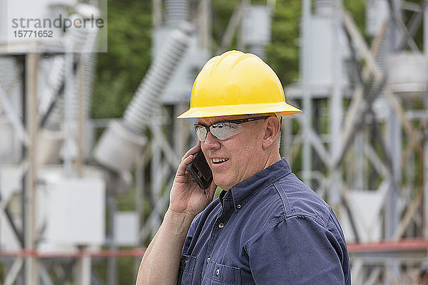 Handwerker telefoniert in einer elektrischen Umspannstation