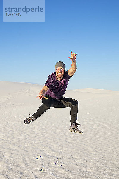 Unbekümmerter Mann in der Luft auf dem weißen Sand mit blauem Himmel  White Sands National Monument; Alamogordo  New Mexico  Vereinigte Staaten von Amerika