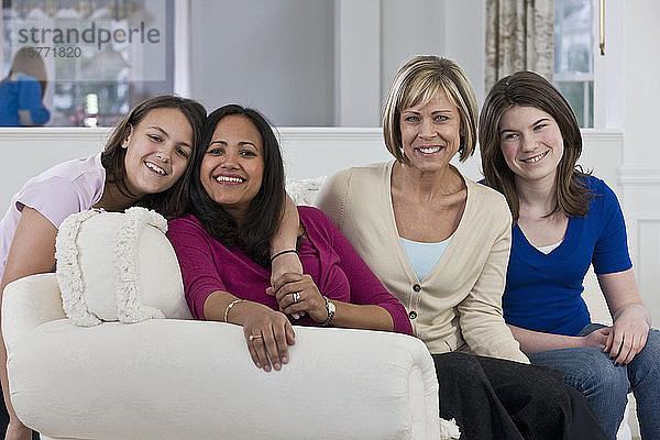 Zwei Mütter mit ihren Töchtern sitzen auf einer Couch in einem Haus