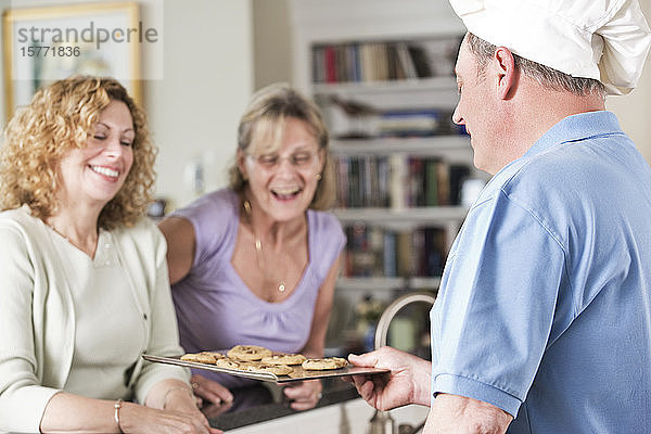 Chefkoch serviert Kekse an reife Frauen zu Hause.