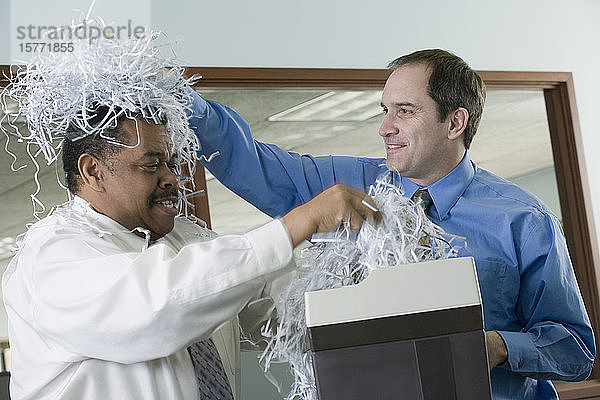 Geschäftsleute spielen mit geschreddertem Papier im Büro