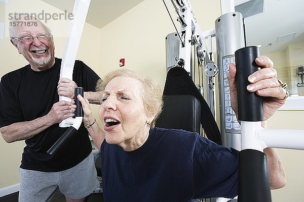 Ein älteres Paar trainiert im Fitnessstudio.