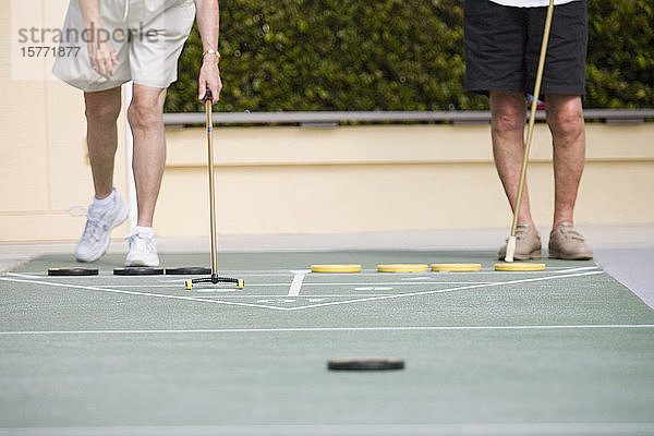 Tiefschnittansicht von zwei älteren Männern  die Shuffleboard spielen