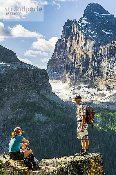 Weiblicher und männlicher Wanderer auf einer felsigen Bergklippe mit Blick auf dramatische Berge in der Ferne  Yoho National Park; Field  British Columbia  Kanada