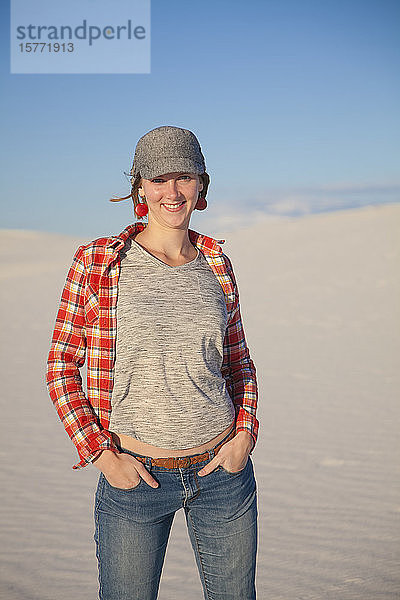 Porträt einer jungen Frau  die auf dem weißen Sand mit blauem Himmel steht  White Sands National Monument; Alamogordo  New Mexico  Vereinigte Staaten von Amerika