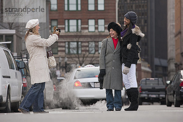 Eine Frau  die ein Foto von Freunden auf einer Straße in der Stadt macht; Boston  Massachusetts  Vereinigte Staaten von Amerika