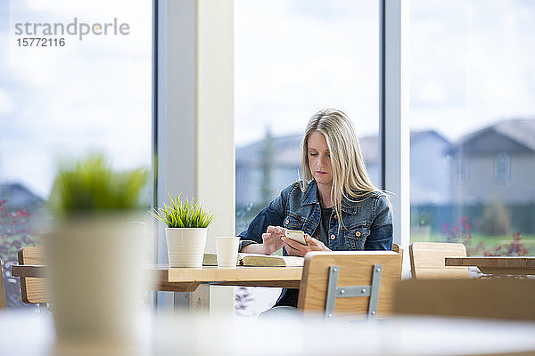 Eine reife Christin studiert ihre Bibel in einem Café und recherchiert zusätzlich auf ihrem Smartphone: Edmonton  Alberta  Kanada