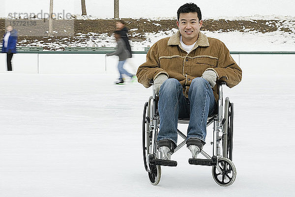 Porträt eines jungen Mannes  der in einem Rollstuhl sitzt