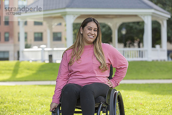 Frau mit Rückenmarksverletzung sitzt im Rollstuhl in einem Park