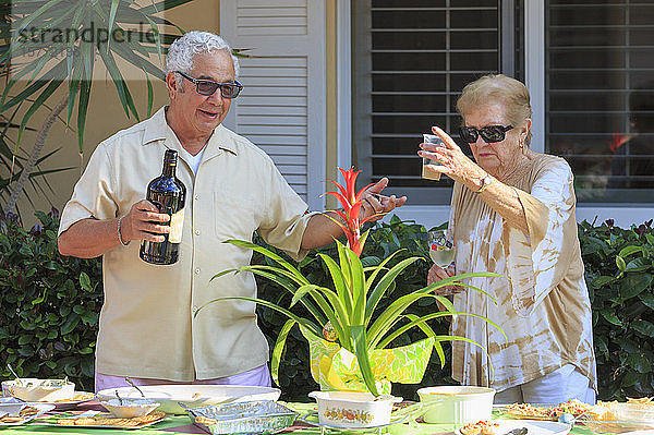 Älteres Paar mit alkoholischen Getränken bei einer Mahlzeit im Freien