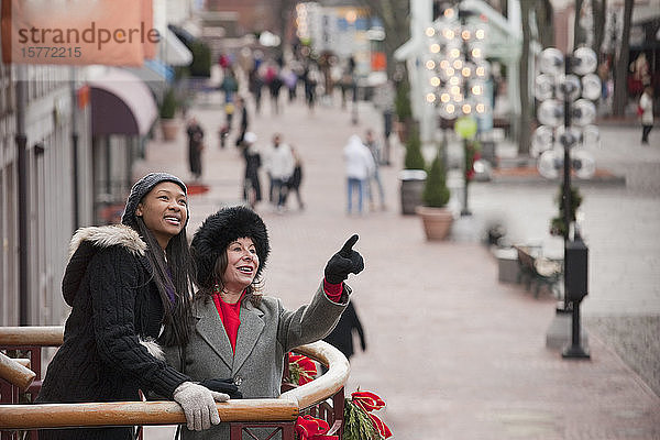 Zwei Frauen stehen auf einem Balkon mit Weihnachtsschmuck und blicken auf die Stadt; Boston  Massachusetts  Vereinigte Staaten von Amerika