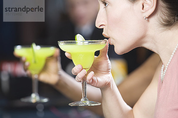 Seitenansicht einer jungen Frau beim Trinken eines Cocktails.