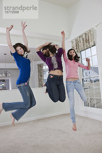 Drei Mädchen im Teenageralter feiern eine Tanzparty  während sie mit Kopfhörern Musik hören