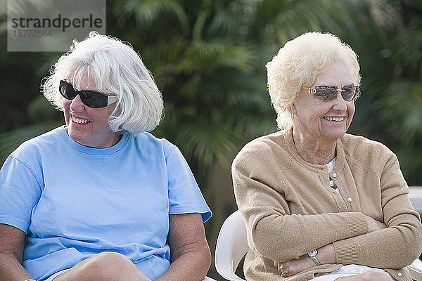 Zwei ältere Frauen sitzen zusammen und lächeln