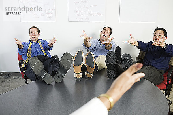 Geschäftsleute gestikulieren mit den Füßen auf dem Schreibtisch.