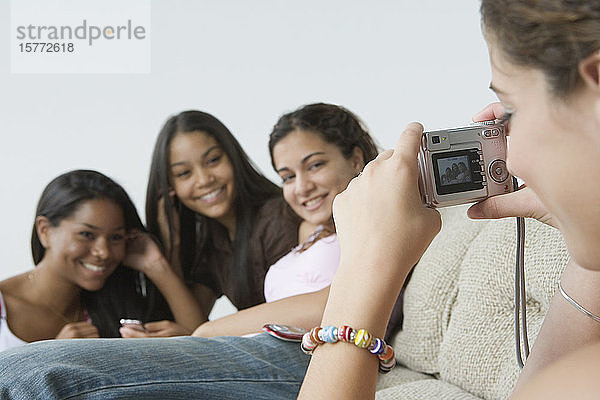 Nahaufnahme eines Mädchens im Teenageralter  das ihre Freunde mit einer Digitalkamera fotografiert