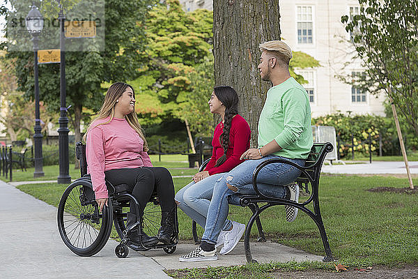 Frau mit Rückenmarksverletzung im Gespräch mit Geschwistern im Park
