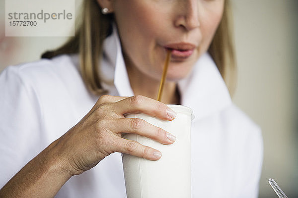 Blick auf eine Frau  die einen Milchshake trinkt.